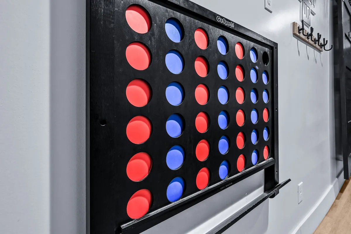 A close-up of a Connect 4 game board, set against a backdrop of a cheerful, active room. The image radiates the joy of family gatherings and playful bonding moments.