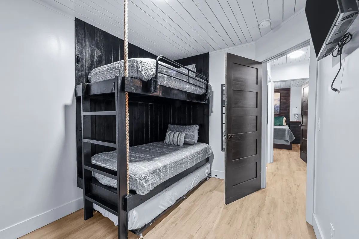 A cozy bunk bedroom with a sturdy bunk bed, playful wall color, and a doorway leading to the rest of the home. The space is inviting, perfect for families or children, offering both sleep and play opportunities.