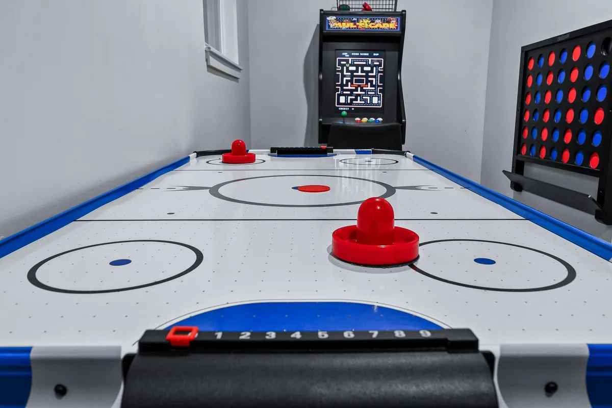 A lively game nook complete with an air hockey table, retro arcade machine, and colorful wall decorations. The compact space is designed for active play and nostalgic fun, inviting guests to immerse in friendly tournaments.